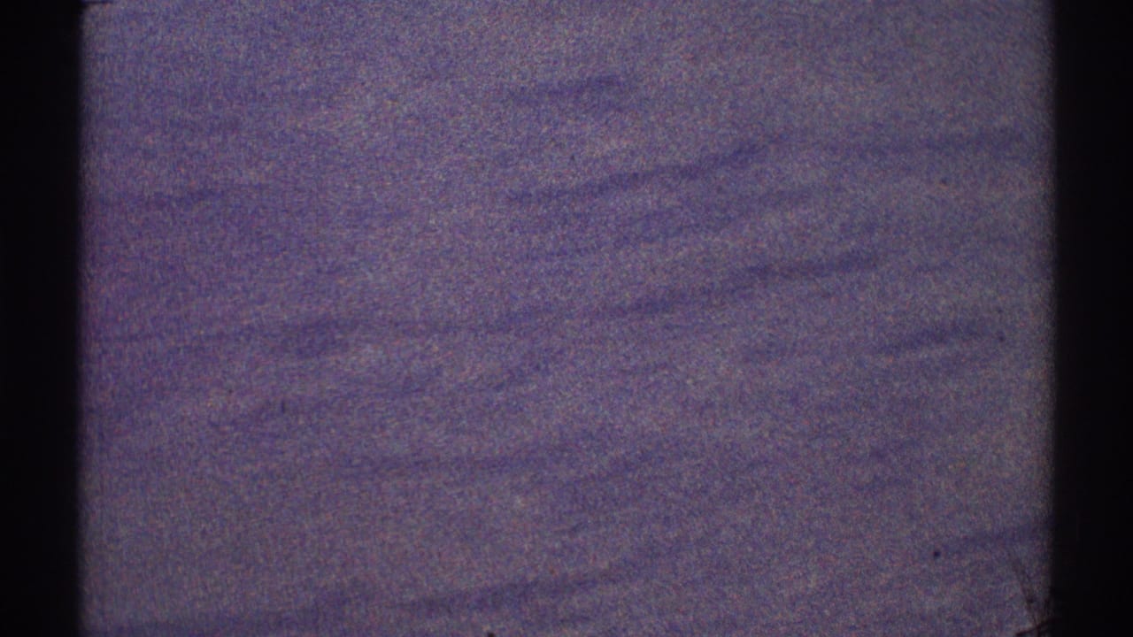 Dark, grainy aircraft-window view over indistinct terrain with purple film tinting.