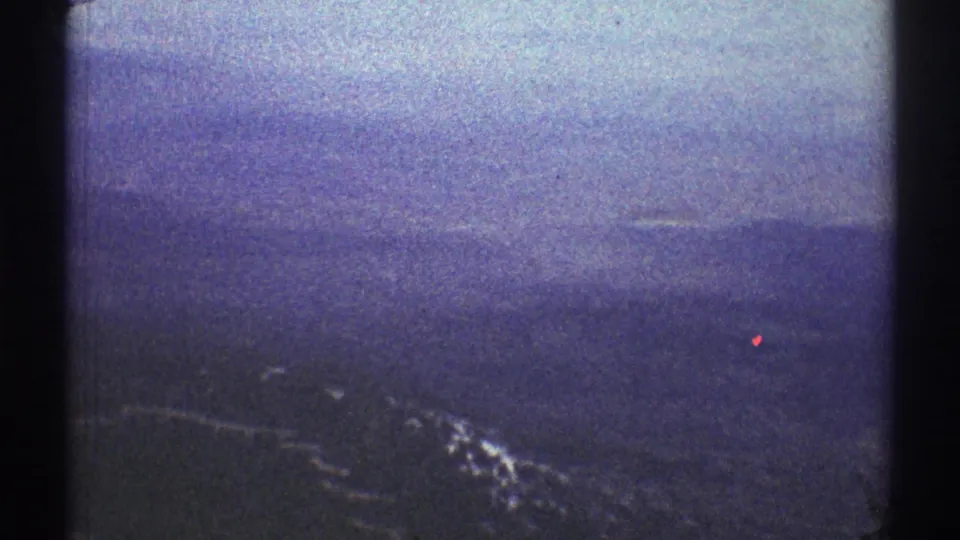 1969 8mm helicopter footage near Los Angeles, looking across distant blue mountain ridges and snow patches through window framing.
