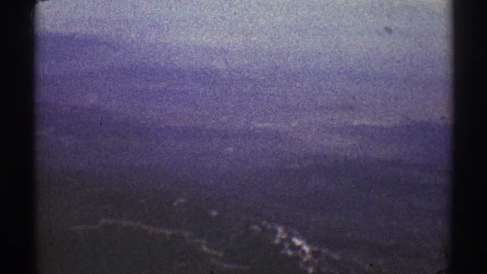 1969 8mm frame from the Los Angeles metadata showing a hazy layered mountain landscape under a pale sky.