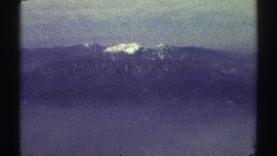 1969 8mm frame showing a distant snow-streaked mountain peak above layered dark hills near Los Angeles metadata.