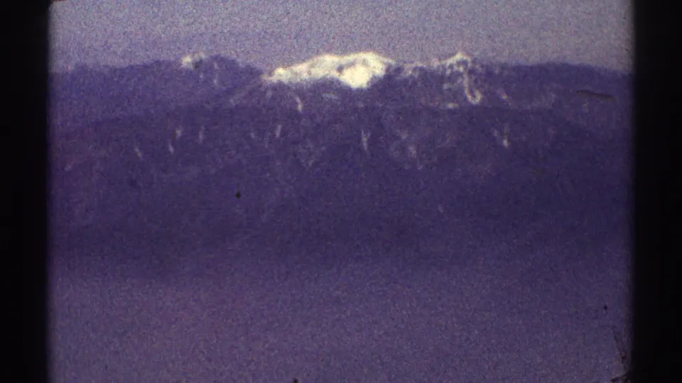 1969 8mm Los Angeles-area view of a bright snow patch on a distant mountain ridge beneath a muted, hazy sky.
