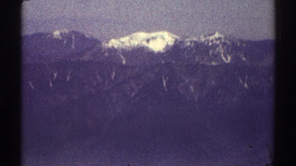 A closer 1969 8mm view of the distant Los Angeles-area mountain ridge, with a white snowy summit against a blue-purple haze.