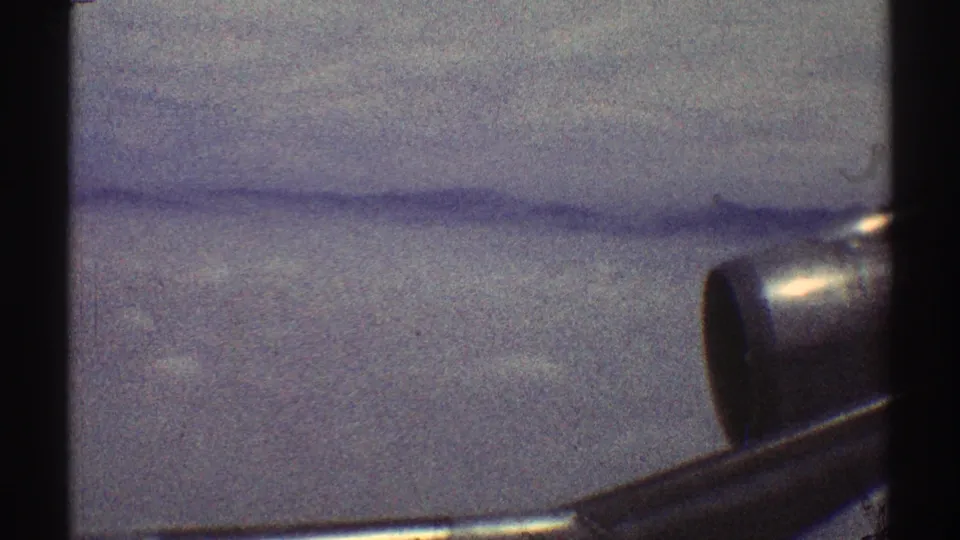 1969 8mm Los Angeles-area mountain view with haze across the ridges and a partial metallic object visible at the right foreground edge.