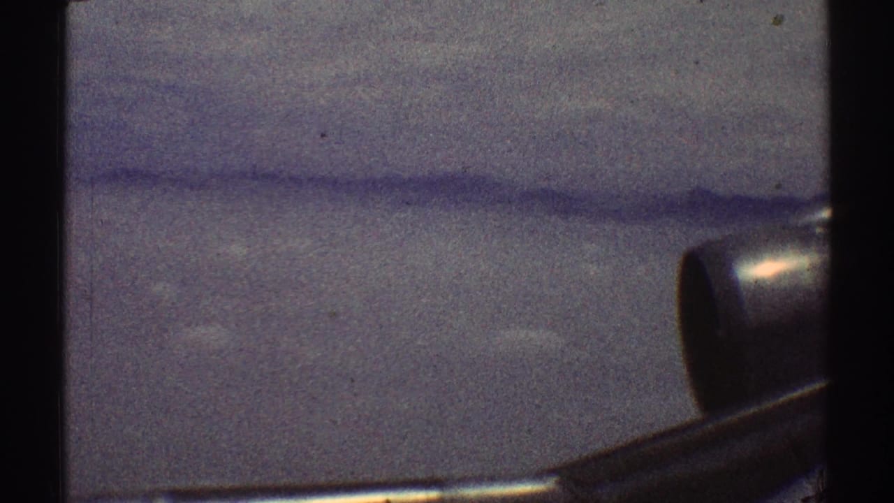 Clouds seen through an airplane window with part of the wing or engine at the right edge.