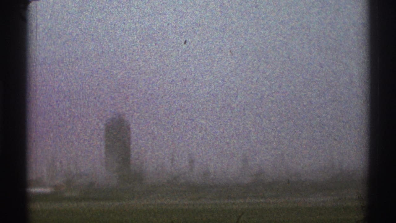 Distant airport control tower seen through haze from a moving vehicle.