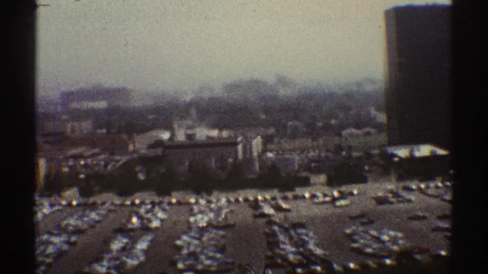 1969 Los Angeles elevated view showing parking lots, rooftops, low buildings, distant haze, and dark film-frame borders.