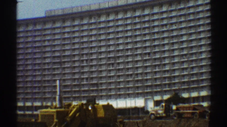 1969 Los Angeles street-level view of a curved multi-story building with repair equipment in front.