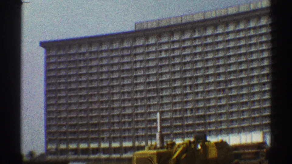 1969 Los Angeles 8mm frame with a large windowed building and construction machinery along the foreground.