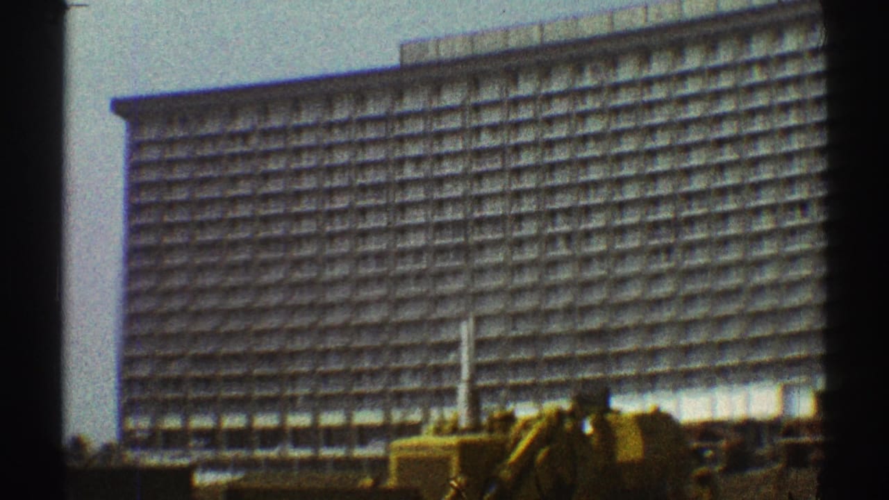 Large multi-story hotel with repeating balcony grid under a hazy sky.