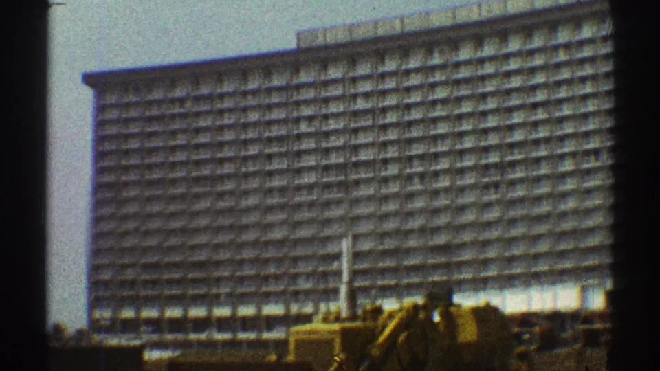 1969 Los Angeles home-movie frame showing a large hotel facade with rows of balconies, soft focus, and dark foreground edges.