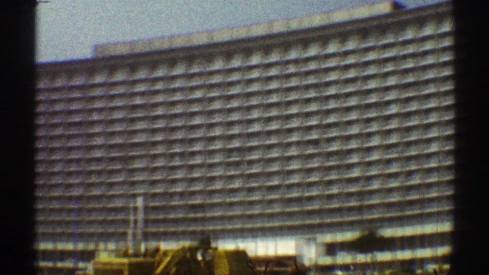 A 1969 Los Angeles exterior view of a massive hotel, partly blocked by a dark vertical strip, with rows of balconies across the facade.