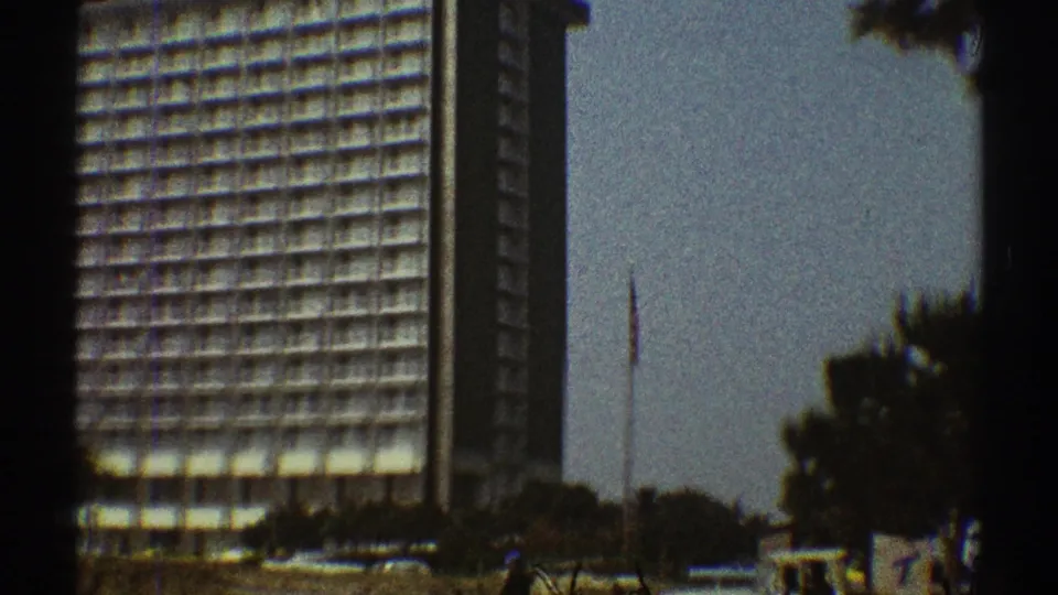 The final 1969 Los Angeles frame shows the hotel from farther right, with a tall side wall, balcony grid, trees, and a thin pole nearby.