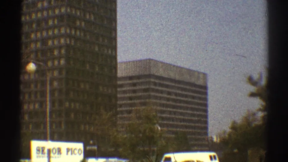 1969 Los Angeles street view with high-rise buildings, a white van, trees, street lamps, and a commercial sign reading partly as Senor Pico.