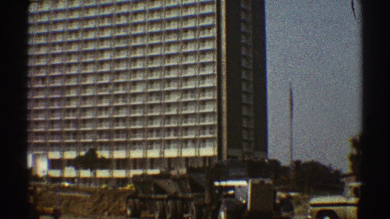High-rise building under construction with gridded facade and equipment in foreground.