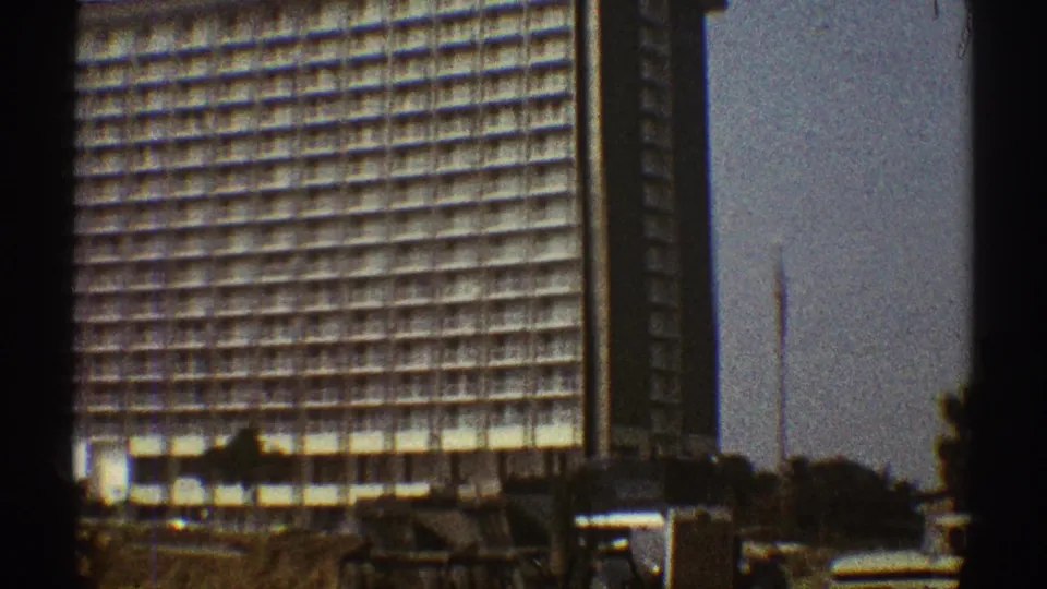 1969 Los Angeles frame with the high-rise facade centered, a dark vertical structural band, construction ground, and equipment below.