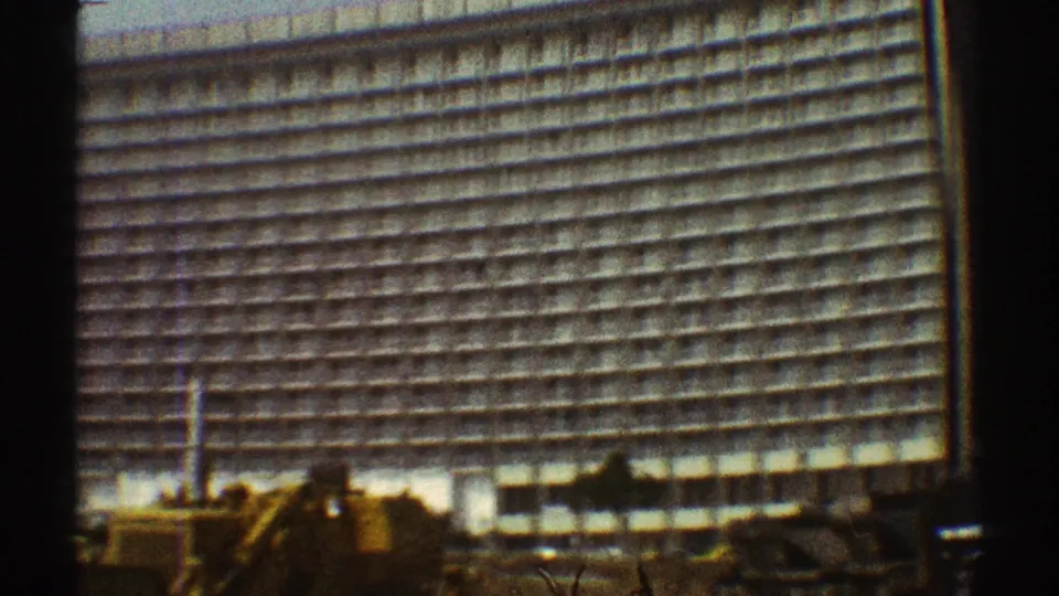 1969 Los Angeles 8mm frame showing a tall apartment or hotel-style high-rise with repeating facade lines and foreground equipment.