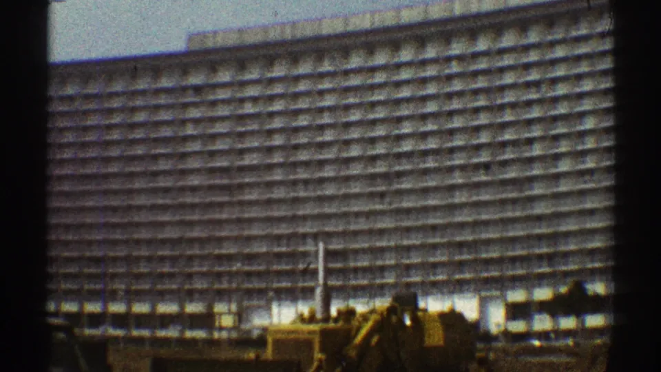 The high-rise fills the frame, its horizontal rows and vertical grid visible above street-level machinery in Los Angeles.