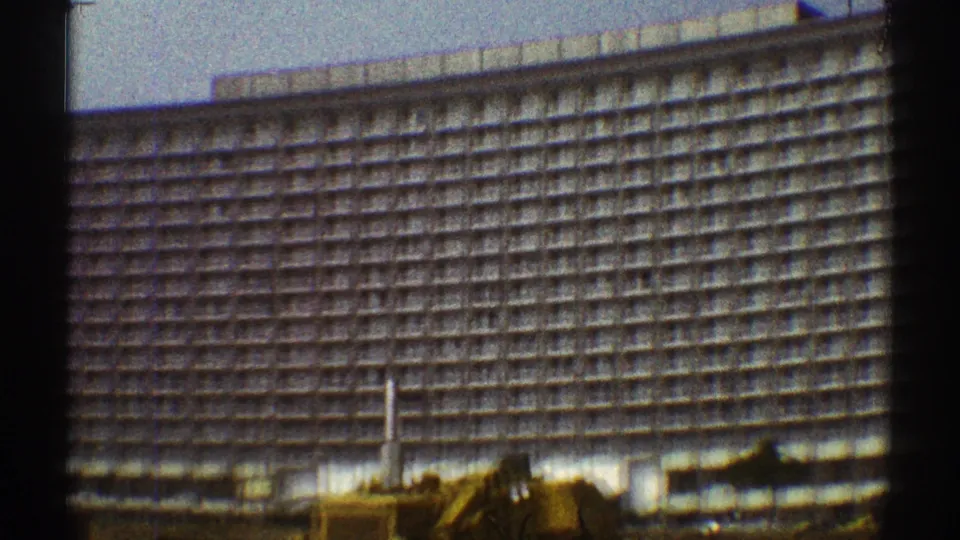 Final frame of the Los Angeles high-rise exterior, showing the repetitive grid facade, street-level equipment, and visible 8mm frame borders.