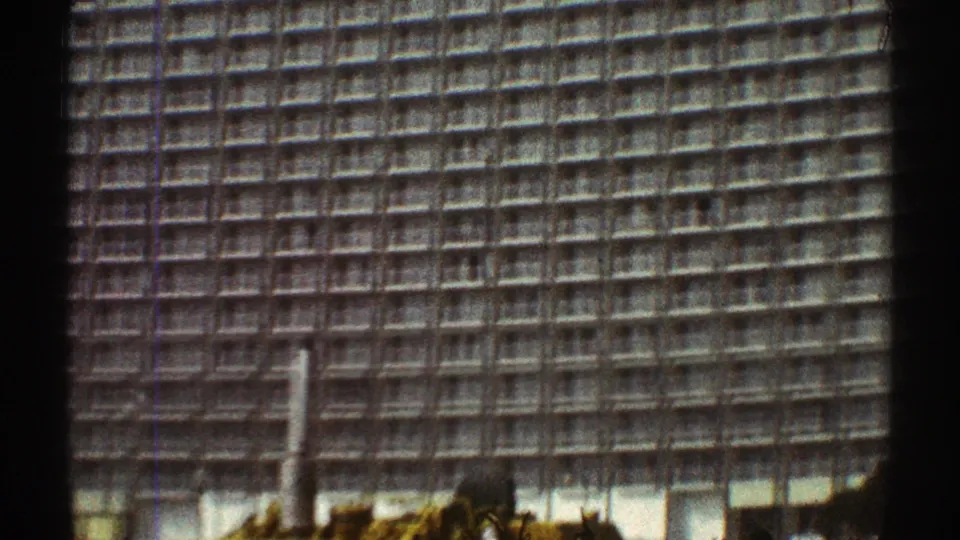 1969 Los Angeles home-movie frame showing a repetitive high-rise facade with construction machinery low in view.