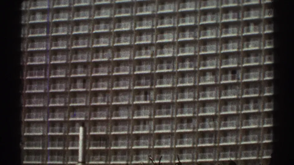 Closer 8mm view of a Los Angeles high-rise facade in 1969, with a construction pole at the lower edge.