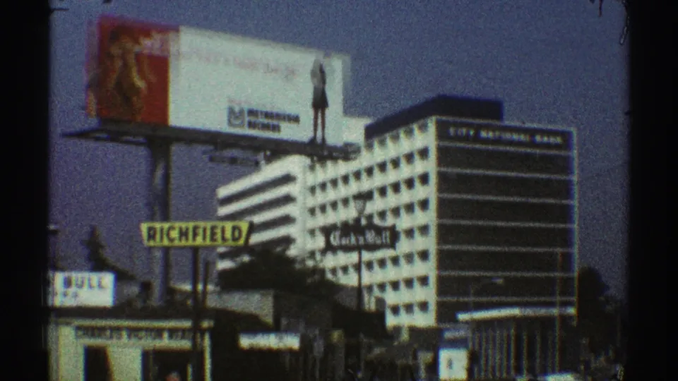 1969 Los Angeles street frame with Richfield and Cock n Bull signage below a large billboard and striped commercial building.