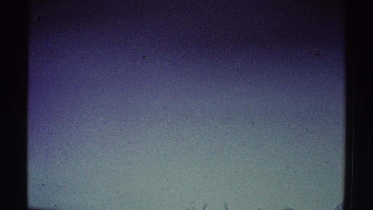 Dark grainy wall area with little visible detail and film gate edges.