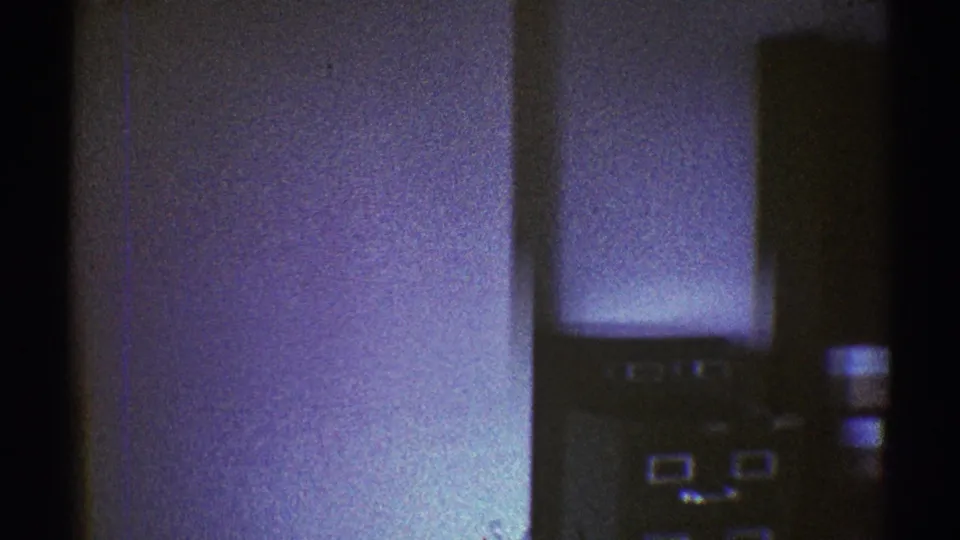 A dim 1969 storage-room frame shows a pale wall, dark cabinet surfaces, possible file drawers, and stacked items along the right edge.