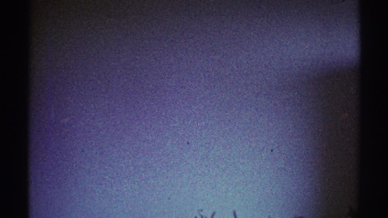 1969 Los Angeles 8mm frame showing a dim plain interior wall with a dark edge and cool color shift.