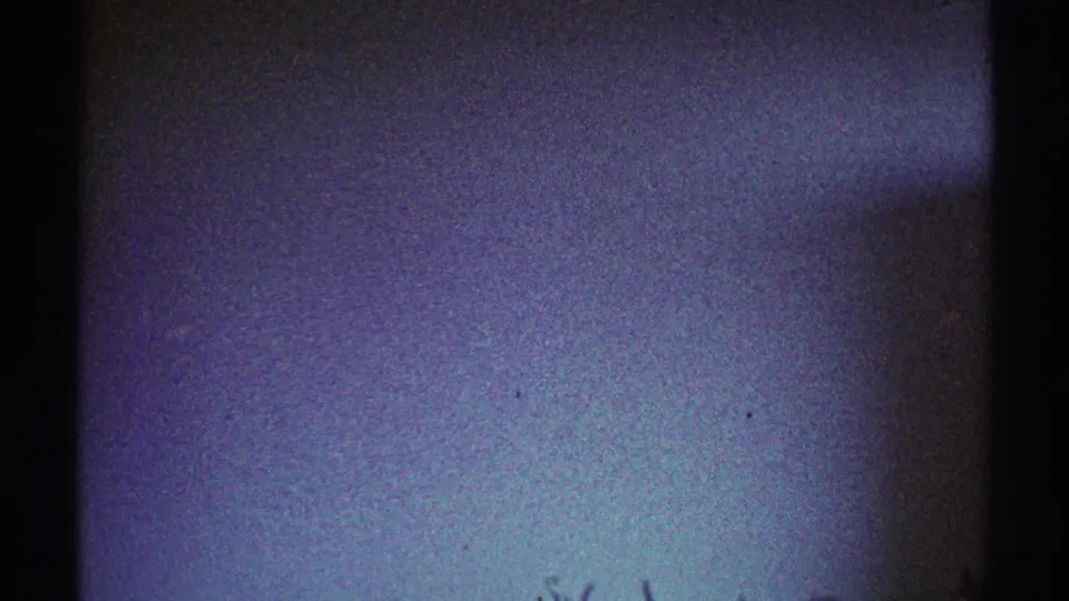 1969 Los Angeles 8mm frame showing a dim plain interior wall with a dark edge and cool color shift.