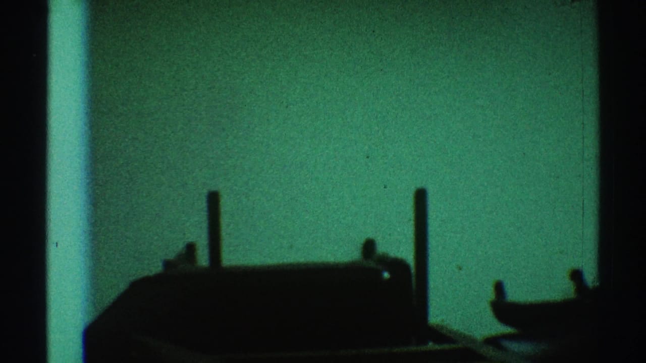 1969 Los Angeles 8mm frame showing dark wooden furniture shapes silhouetted against a green-tinted interior background.