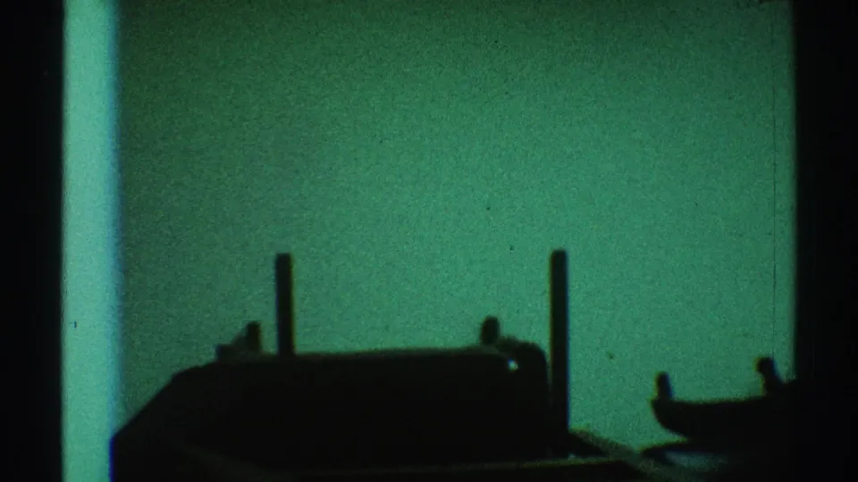 1969 Los Angeles 8mm frame showing dark wooden furniture shapes silhouetted against a green-tinted interior background.