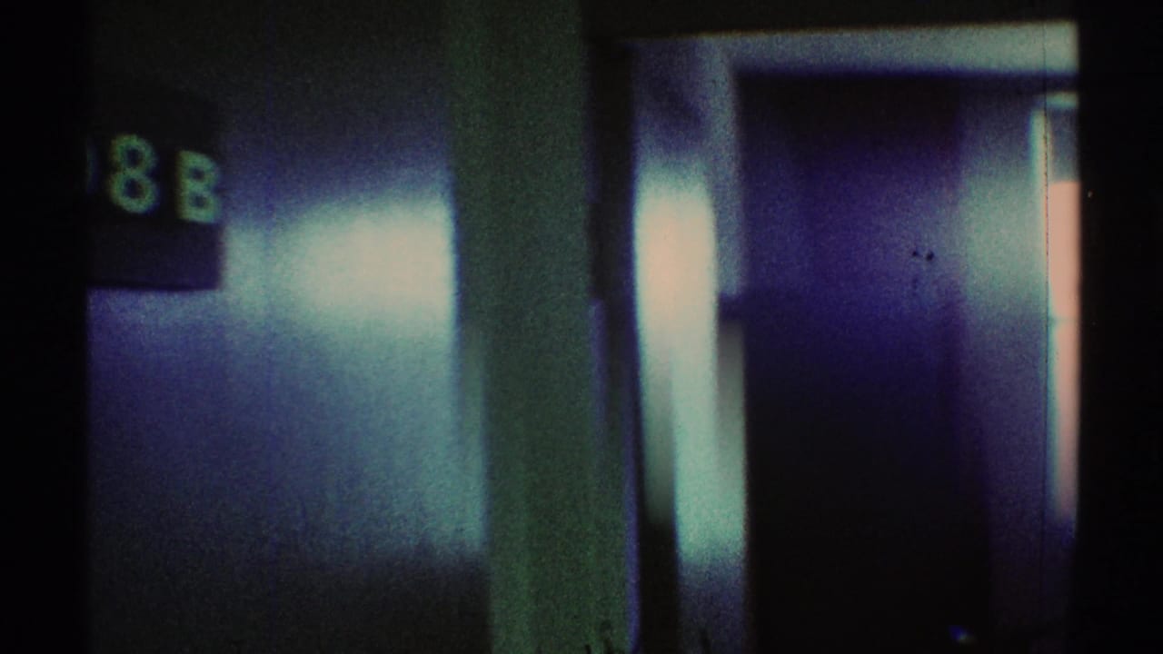 Dark hallway detail with a partially visible room-number sign and reflective doorway surface.