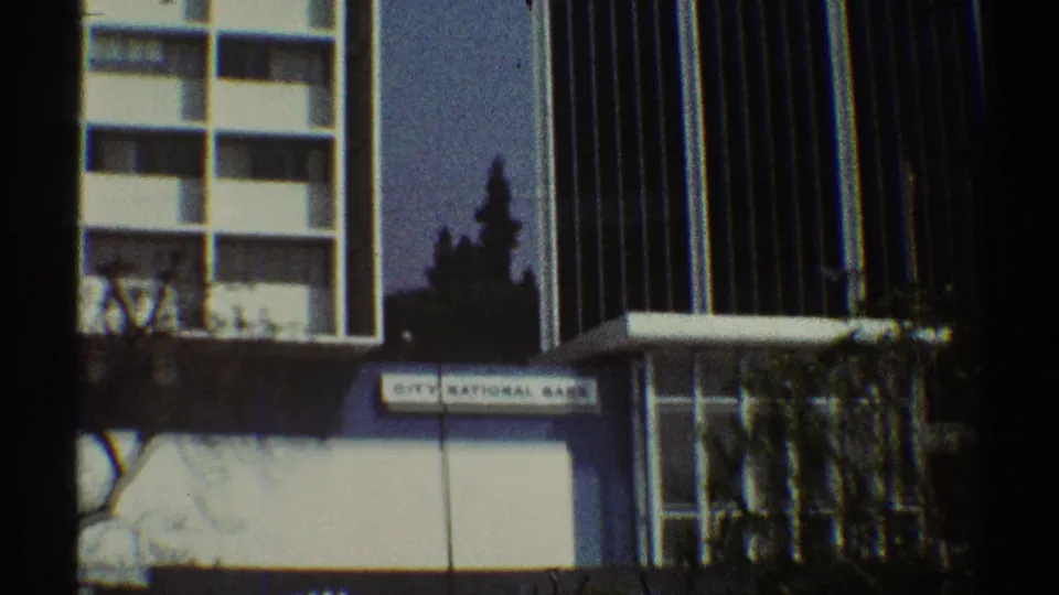 1969 Los Angeles 8mm frame showing an exterior city building facade with a City National Bank sign and surrounding downtown architecture.