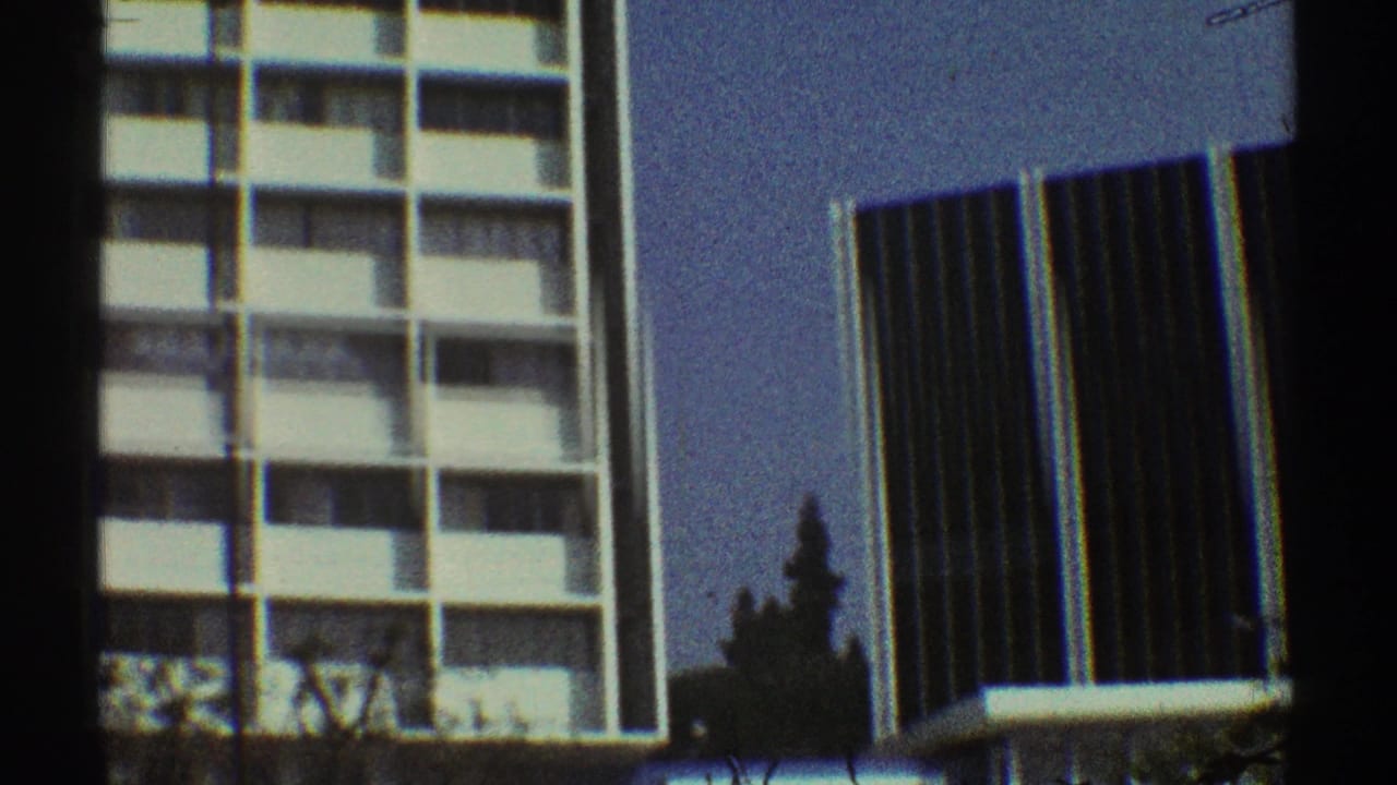 1969 Los Angeles 8mm view of a mid-century apartment block with repeating balconies and a dark tower behind it.