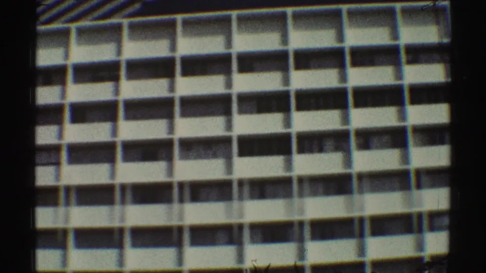 1969 Los Angeles 8mm frame of the lower apartment stories, showing repeated balcony bays and soft film color.