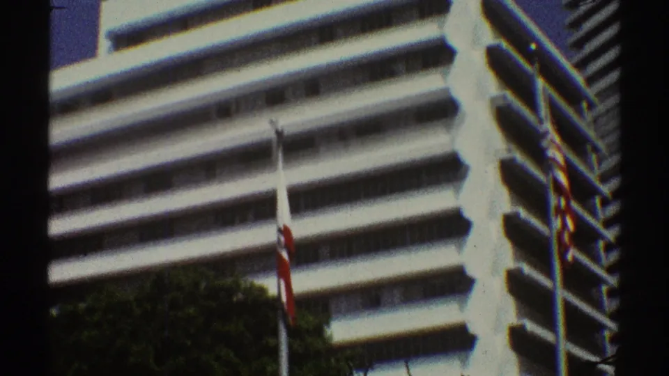 1969 Los Angeles home-movie view of a white office building with broad balconies, a flagpole, and trees below.