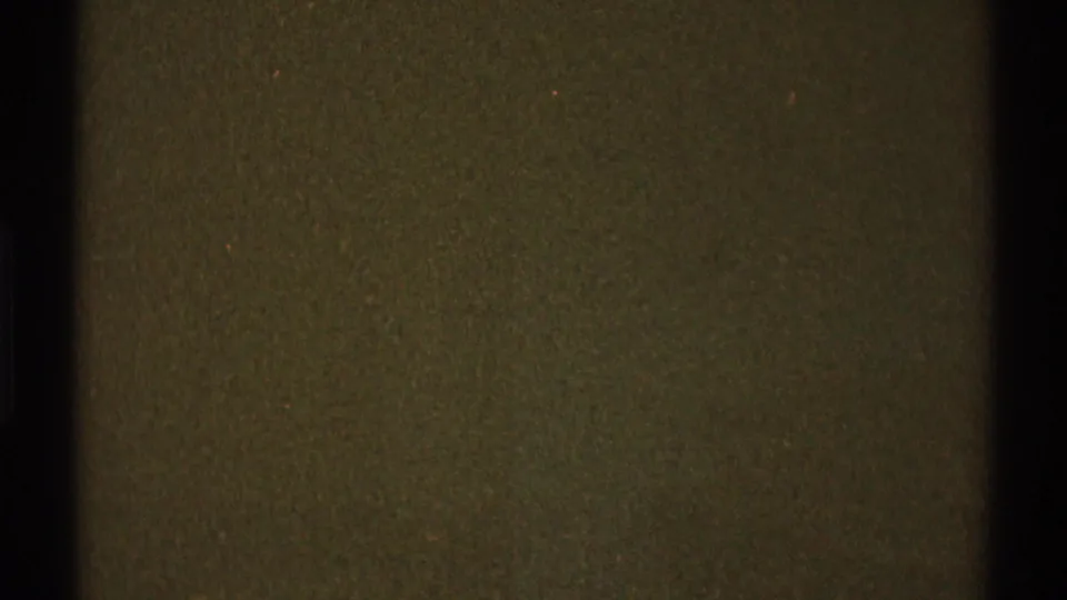 Low-light 1969 8mm frame from Los Angeles metadata showing an indistinct olive surface with gate edge and grain.