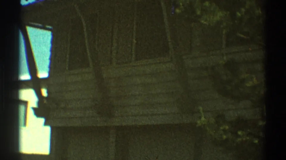 1969 Los Angeles residential exterior with closed windows, siding, roofline, and surrounding trees in soft 8mm color.