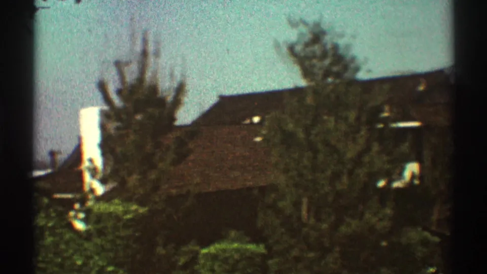 1969 Los Angeles home-movie view of neighboring houses and trees, partially obscured by a dark vertical film or window edge.