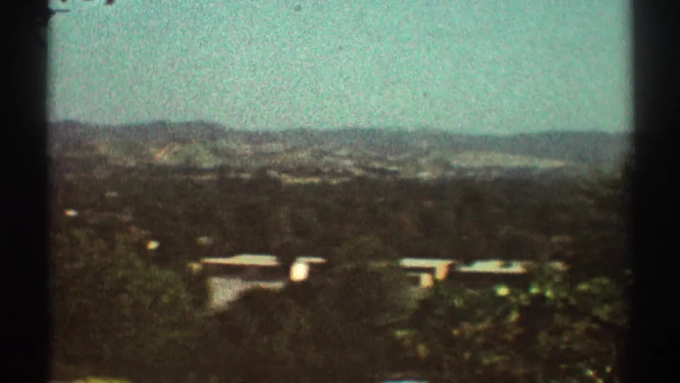 Elevated 1969 Los Angeles-area view of hazy hills, treetops, and distant flat-roof suburban homes.