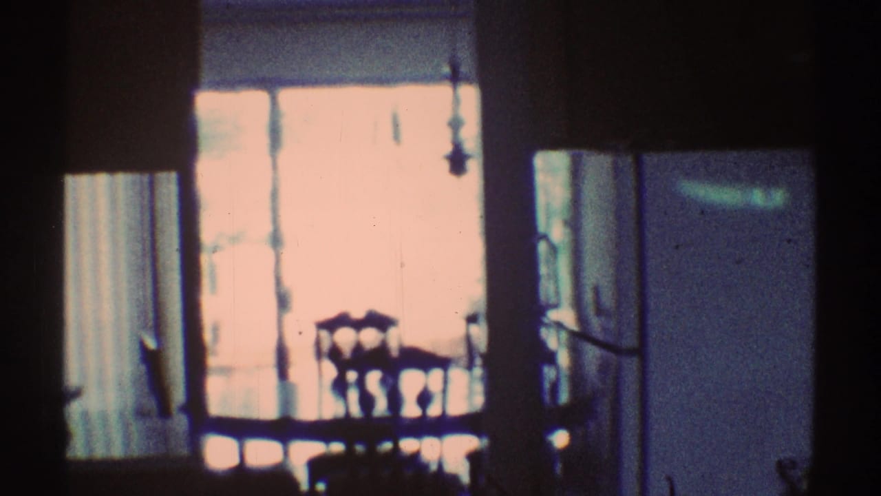 Dim dining area with chairs and table silhouetted near a bright window.