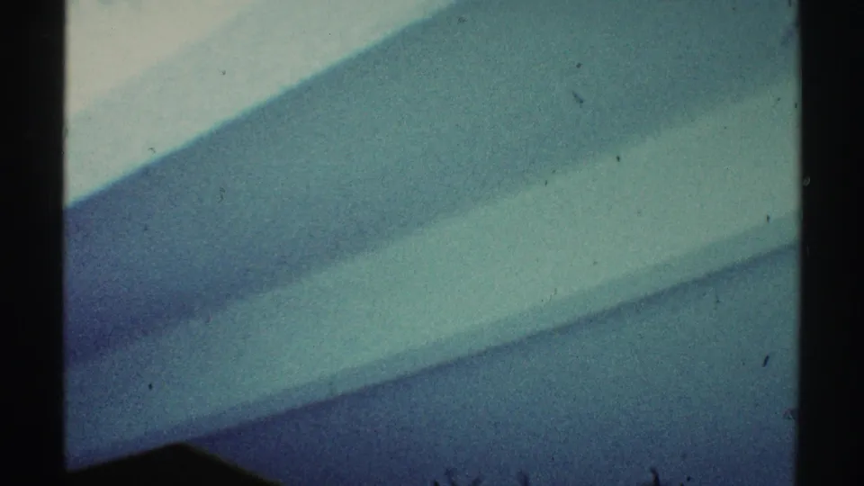 Abstract 8mm interior view from Los Angeles in 1969, with teal wall surfaces, a dark divider, and diagonal shadow bands.