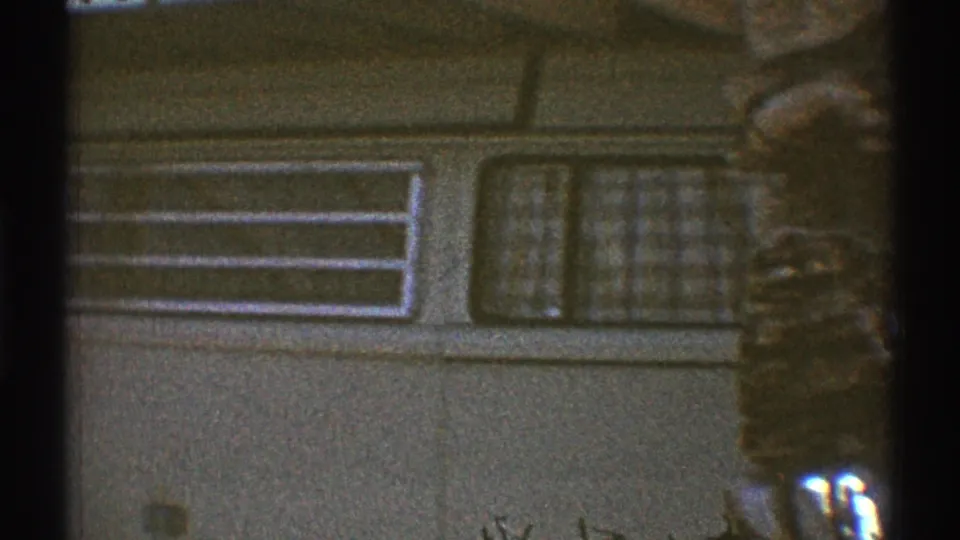 1969 Los Angeles frame showing a residential garage door, window, and nearby tree during a slow pan.