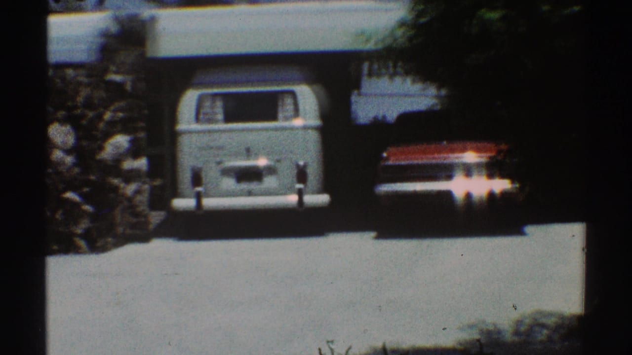 Light blue van parked in a garage beside a white residential exterior.