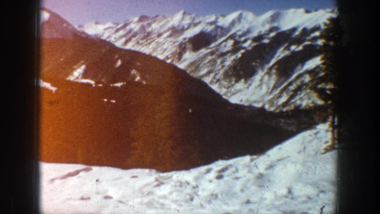 Snowy mountain peaks and a dark slope viewed through an 8mm film frame.