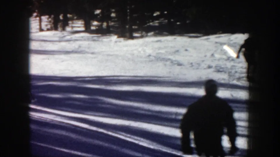 A near silhouetted skier passes at the bottom of the Aspen slope while another figure exits near the right edge.