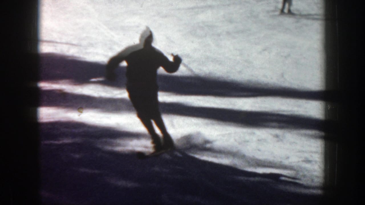 Skier turns on a snowy slope with a dark shadow band behind them.