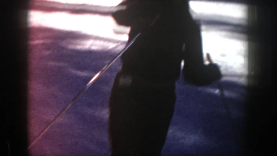A close, underexposed view shows the skier passing near the camera, with one pole visible against the snow.
