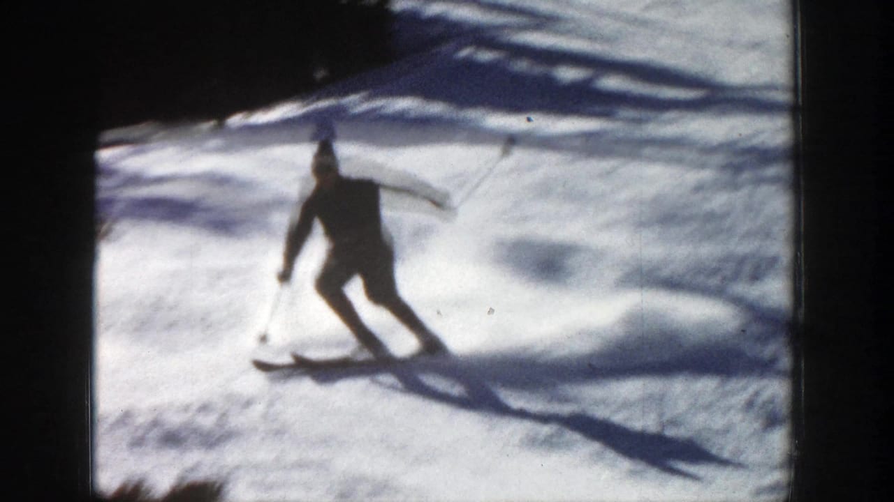 1961 Aspen, Colorado 8mm frame showing a distant skier in dark winter clothing turning across a bright snowy slope.
