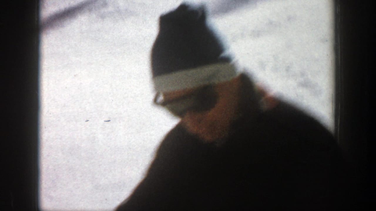 A bundled adult man in a knit cap stands in a snowy Aspen, Colorado landscape in 1961 home-movie footage.